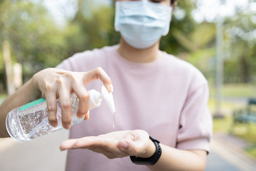 Persona con mascarilla se desinfecta las manos con hidroalcohol