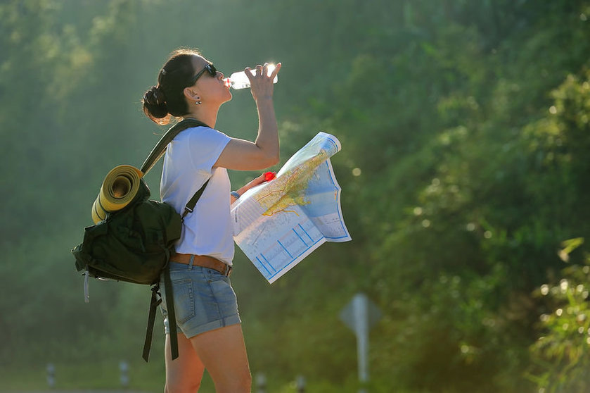 39336327 - woman tourist with backpack drinking water in nature