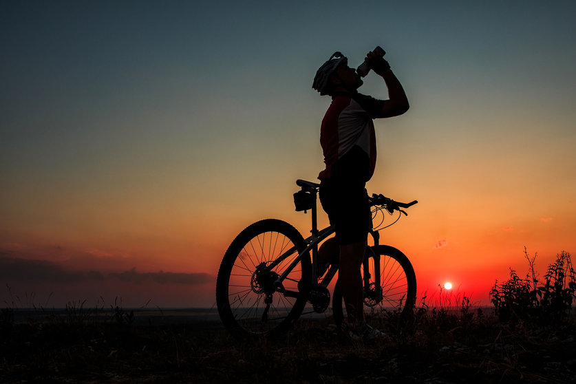 42787124 - silhouette of a biker drinking from bottle on sunset