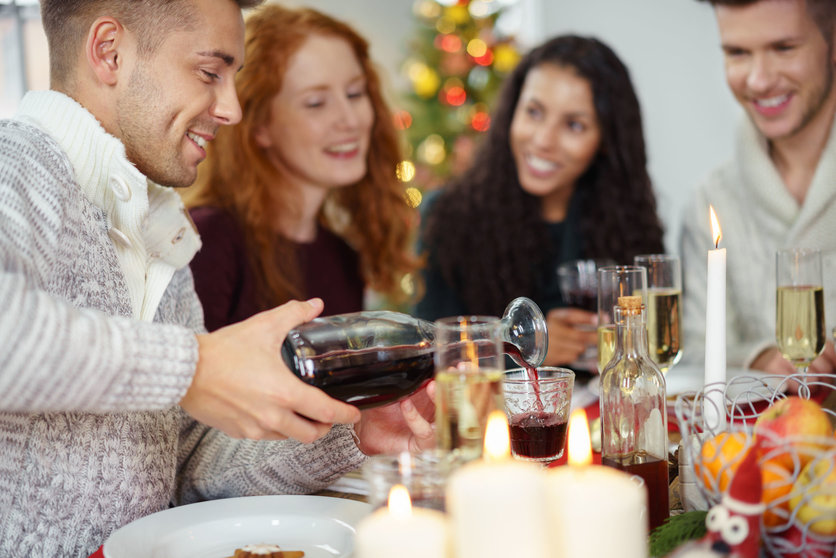 man pouring wine to his friend´s glas while having christmas dinner