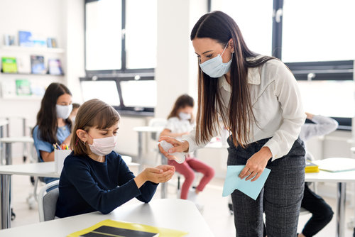 Profesora reparte gel a los alumnos para prevenir contagios de la Covid-19